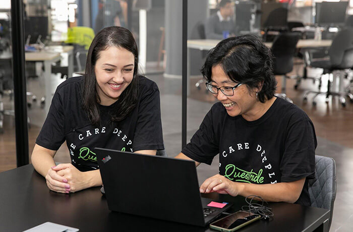Two women sitting at the table and looking at a laptop screen