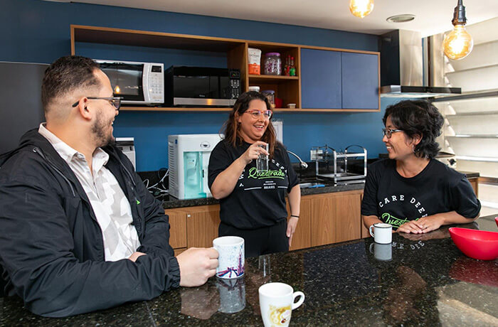 Three people having coffe in the office kitche